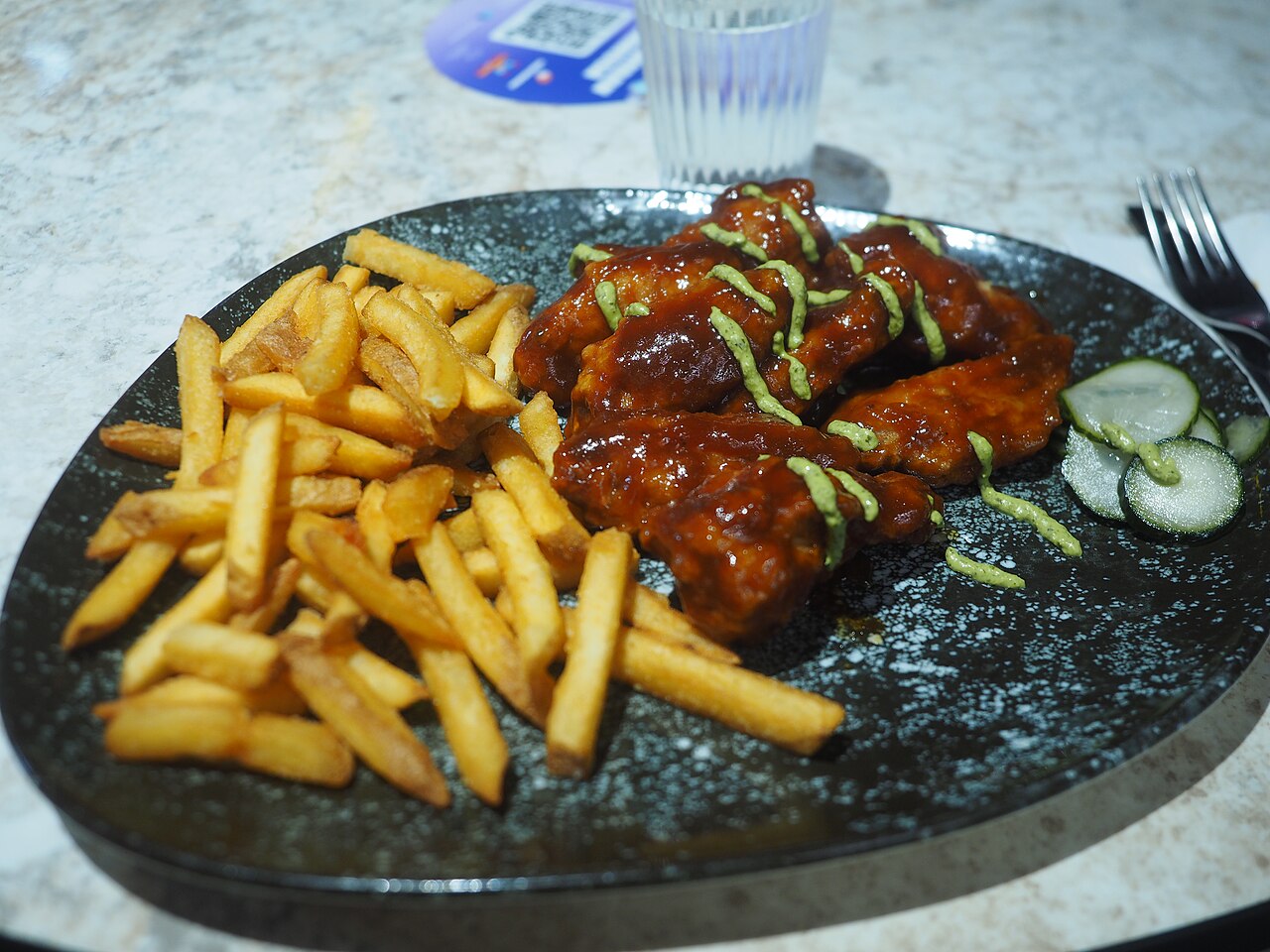 A plate of chicken wings and French fries served for lunch at restaurant Pretty Boy Wingery in the Redi shopping centre in Kalasatama, Helsinki, Finland in August 2026.