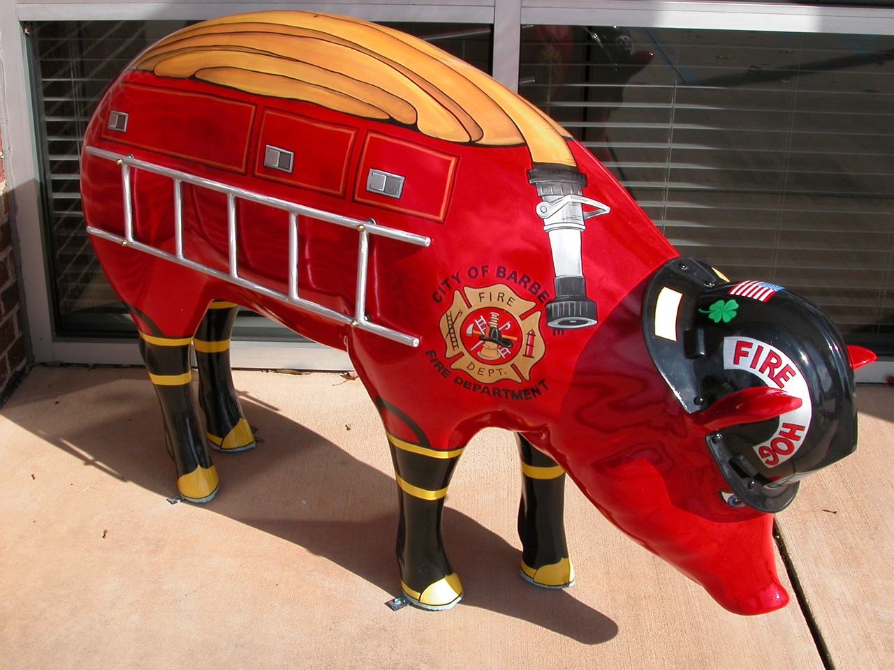 Fire Hog: a pig sculpture painted as a red fire engine, with ladders down the side, a fire department crest on the shoulder, black-and-yellow boots on its legs and a black fire helmet over the snout.