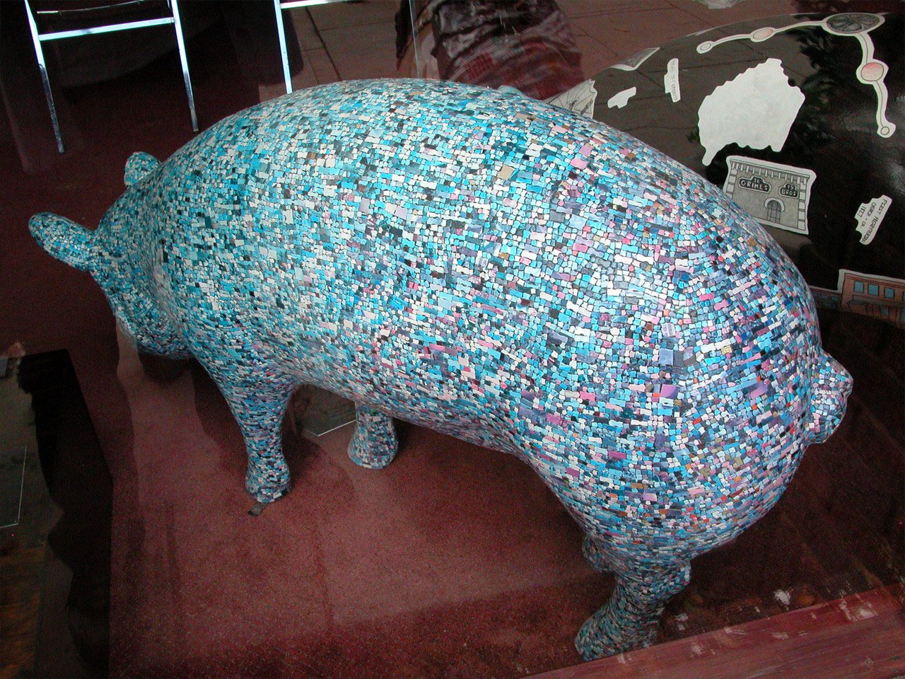 Pigsaw: a pig sculpture covered all over in jigsaw pieces, blue, white and pink.