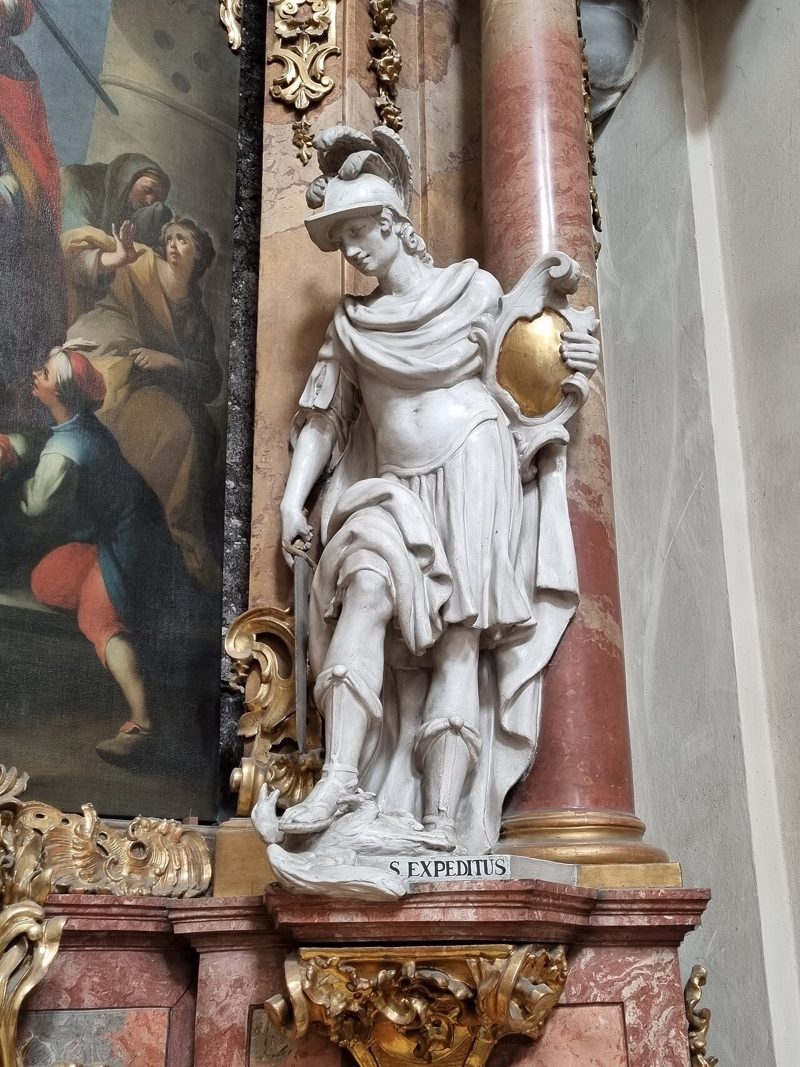 White and gold statue of Saint Expedite in Roman armour, on a baroque altar in Brno.