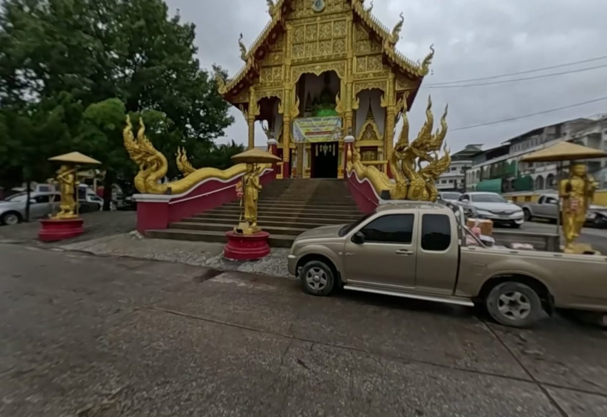 Golden ubosot front with naga stairs and golden standing figures under parasols