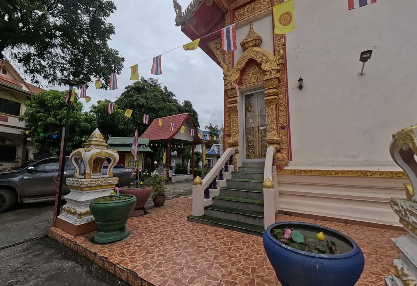 Gilded doorway and steps of the ubosot with lotus bowls and flags