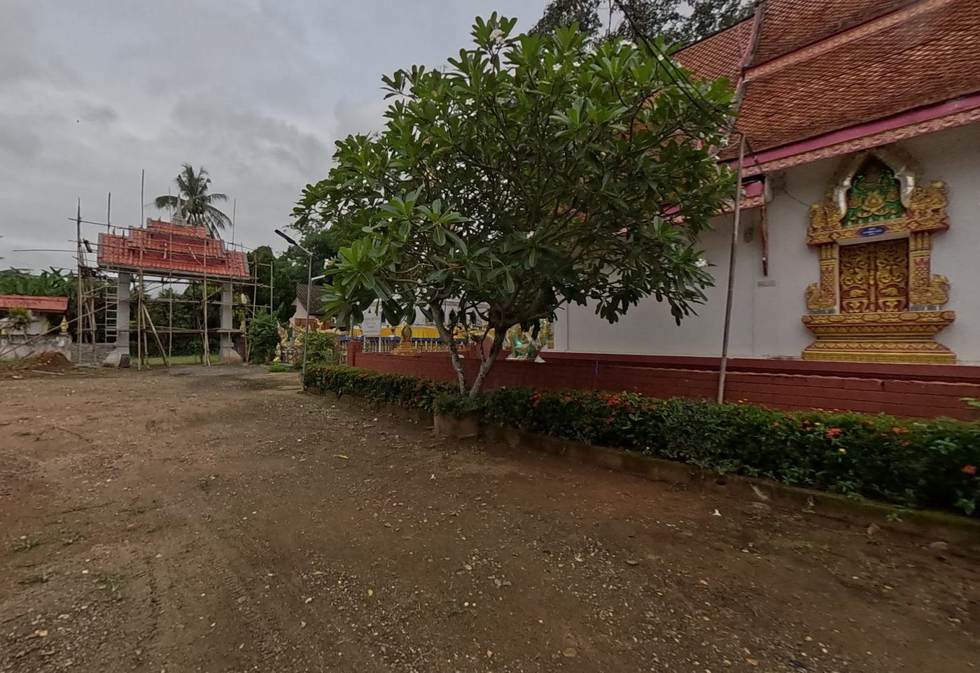 Viharn side with gilded window and a new gate under scaffolding