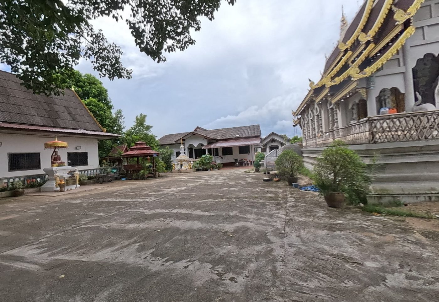 Temple courtyard: monk statue under umbrella, sala and viharn