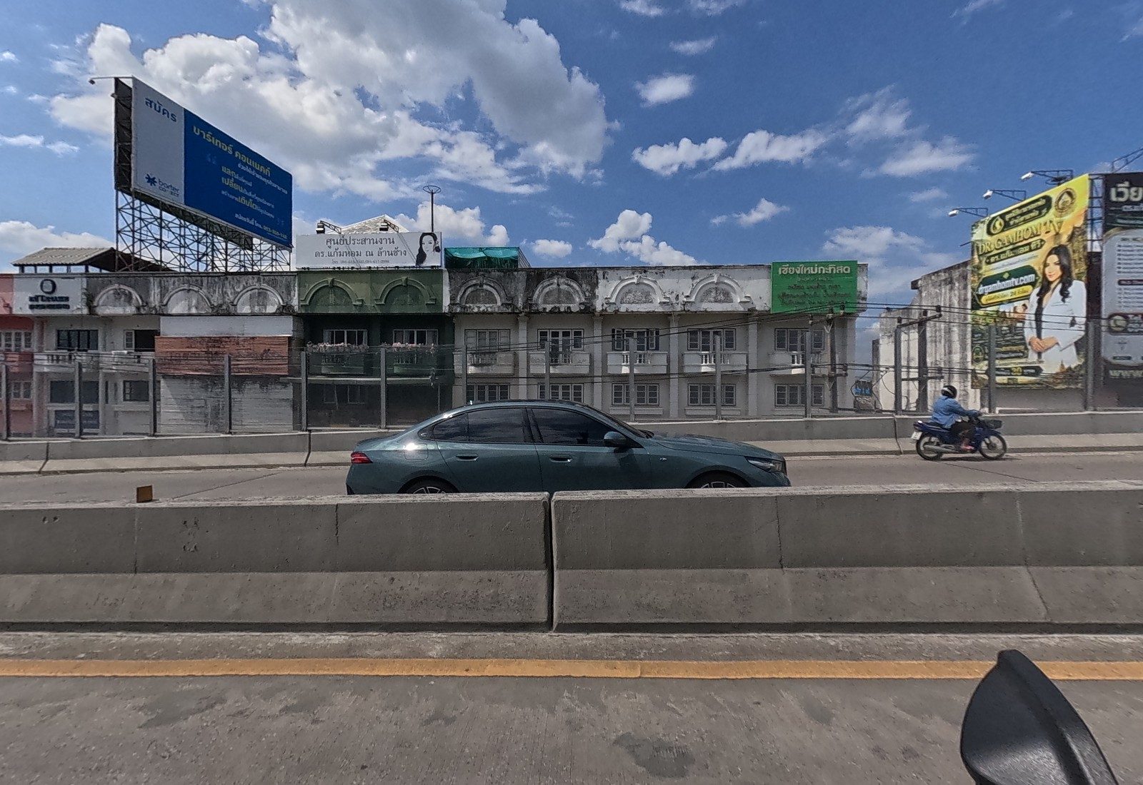 Across the flyover, a row of weathered three-storey colonial-style shophouses with a green shop sign and rooftop billboards.
