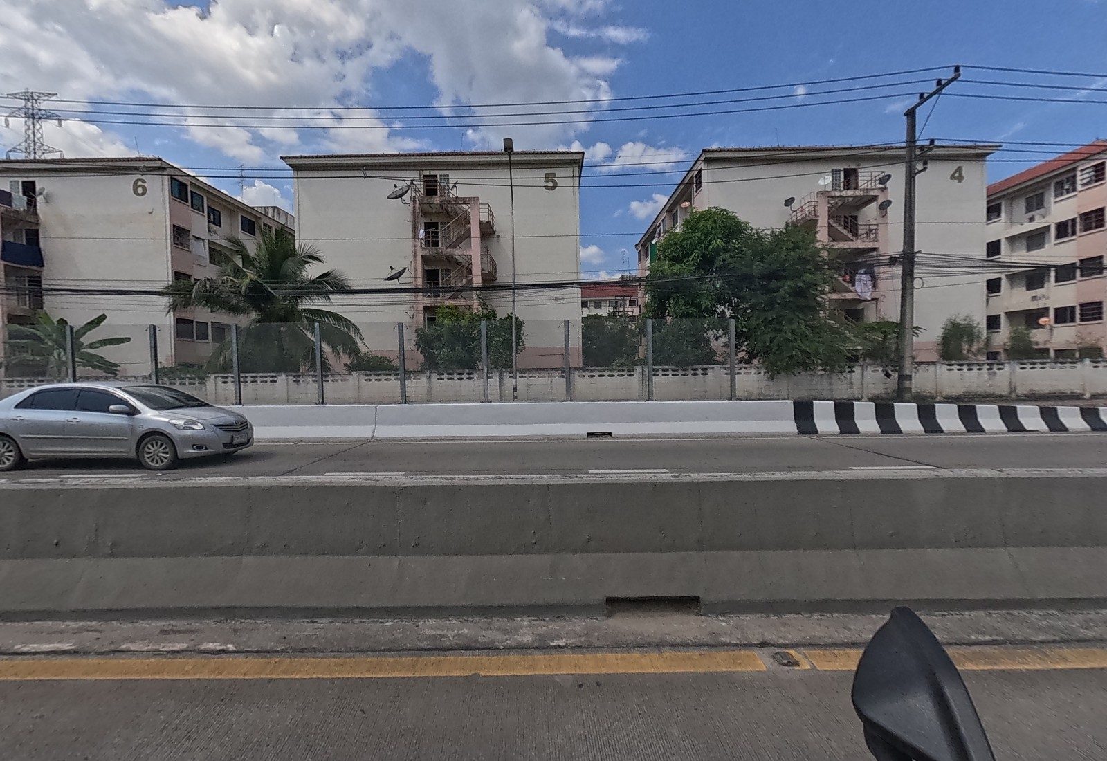 Across the median, Baan Ua Arthorn blocks 6, 5 and 4 stand behind a wall and clear noise panels.
