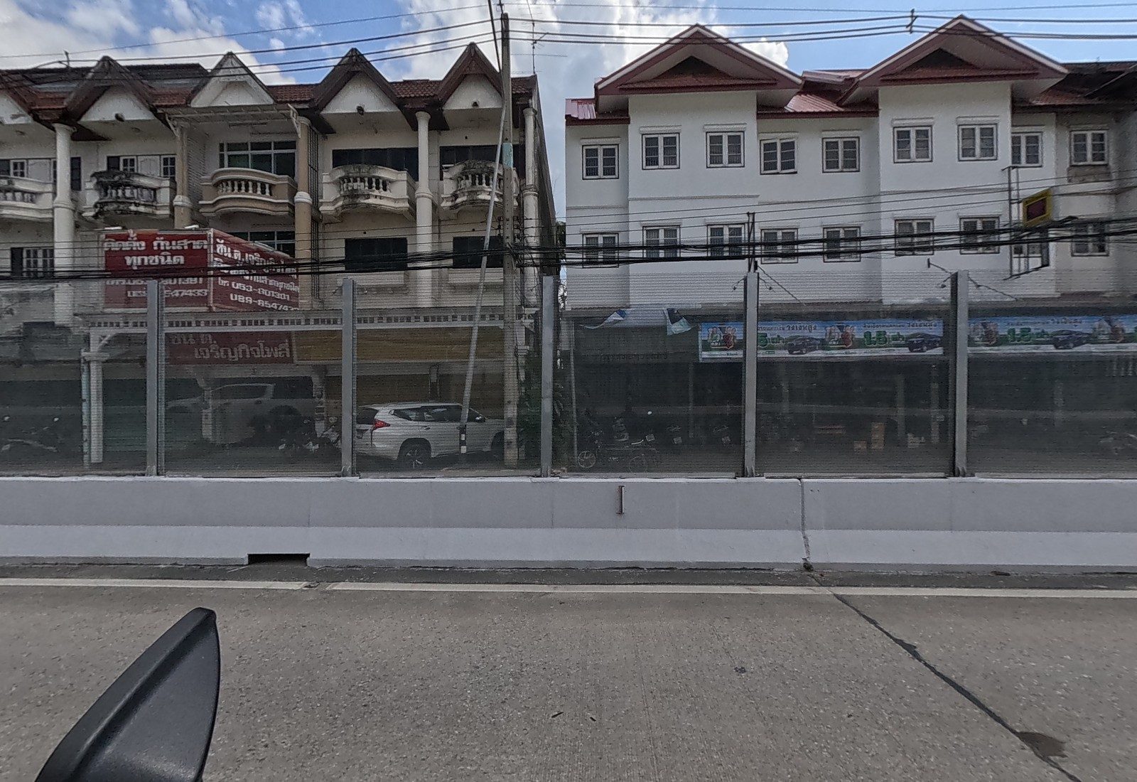 Below the flyover, a shophouse with red signs for an awning installer, and a white shophouse row with a long car-ad banner.