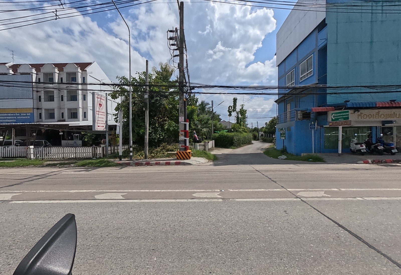 A soi mouth between a white apartment block with a Chang sign and a blue building housing a costume-hire shop.