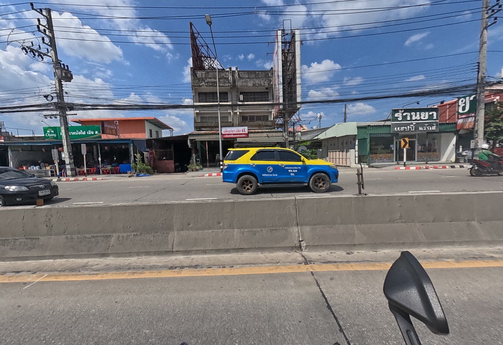 Across the road, an open-front fish-head hotpot eatery, a roast-duck shop in an old three-storey building, and the Happy Drugs pharmacy; a yellow-and-blue taxi passes.