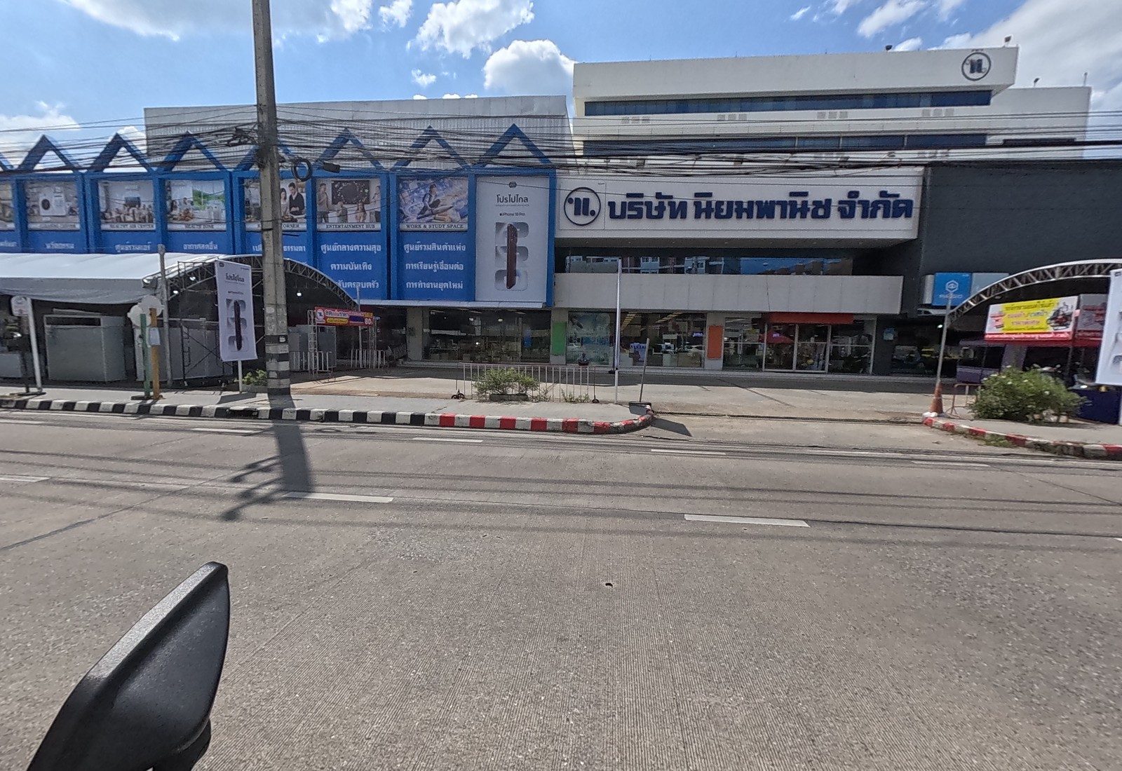 Front of the Niyom Phanich company building with its logo, department fascia and an arched tent at the side.