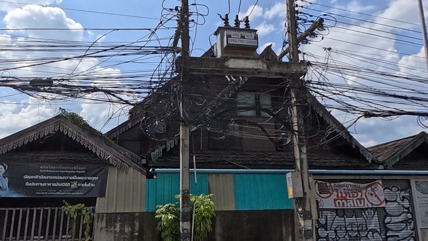Old dark-wood Lanna house behind a walled compound