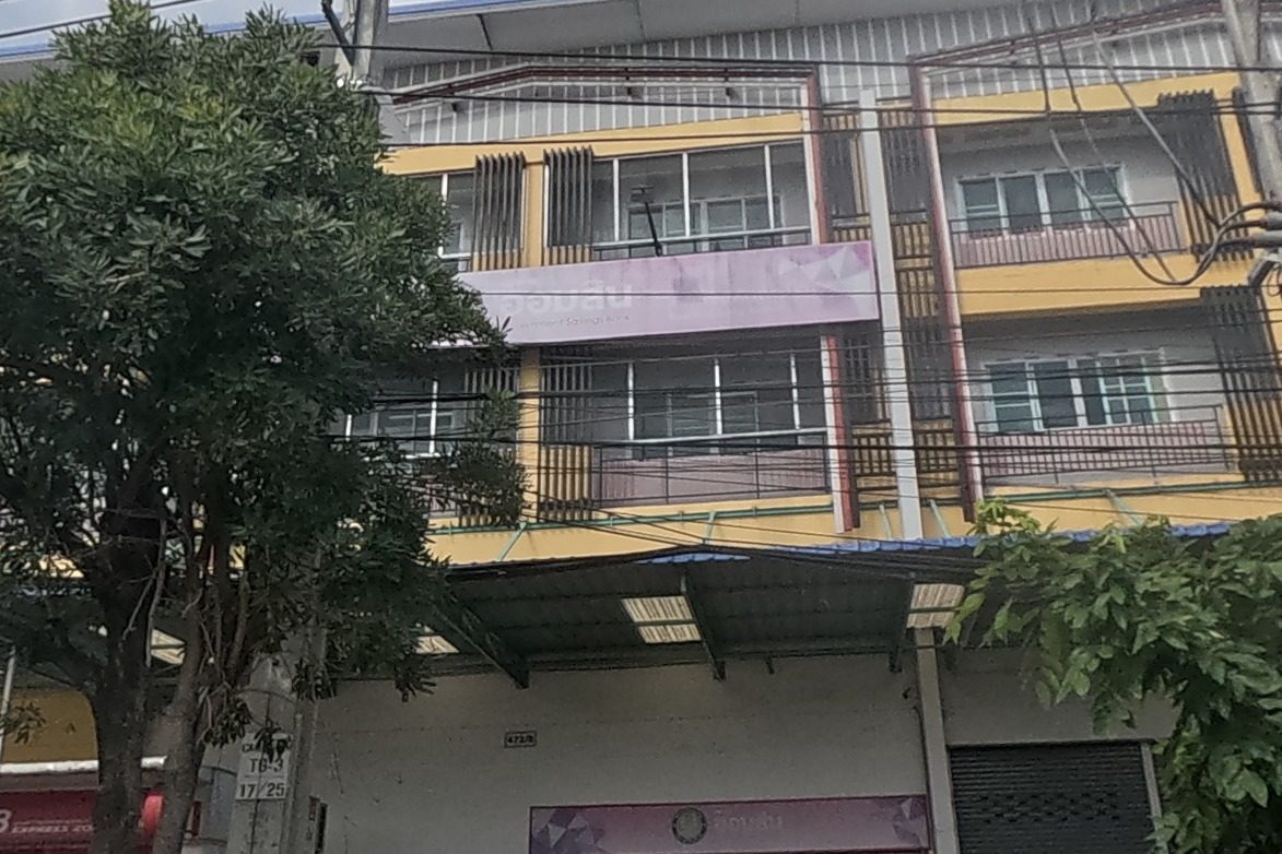 A Government Savings Bank (GSB) branch with an ATM and a home-loan promotion poster stands roadside.