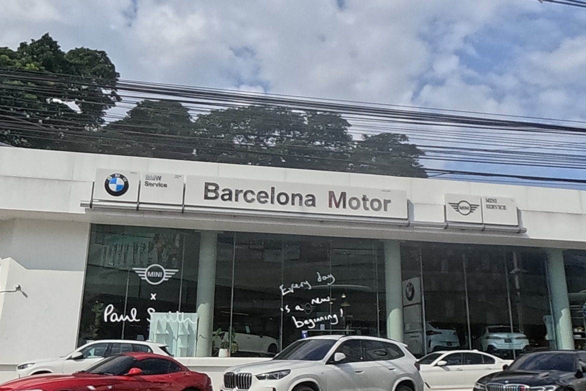 A BMW and MINI car dealership showroom called Barcelona Motor, with cars parked on the forecourt.