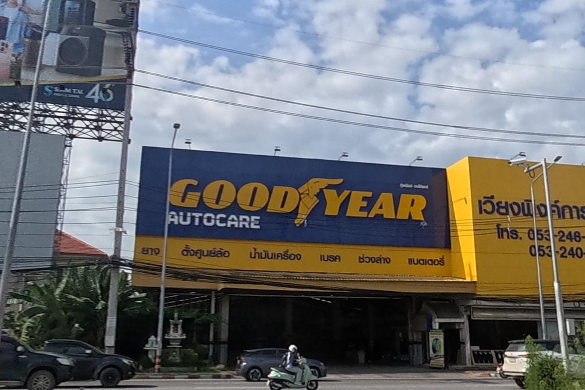 The Goodyear Autocare shop (เวียงพิงค์การยาง) fills a yellow-and-blue building, listing tyres, wheel alignment, oil, brakes, suspension and battery service, a scooter approaching.