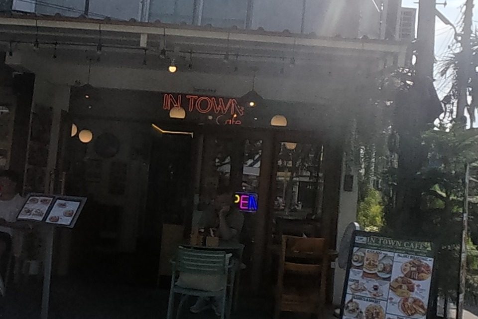 Wendy Tour & Trek travel agency next to In Town Cafe, a lit breakfast cafe with a sandwich-board menu and outdoor seating.