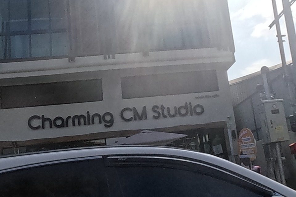 A white SUV passes in front of a Thai-style building housing Moat Moments Cafe and Charming CM Studio.