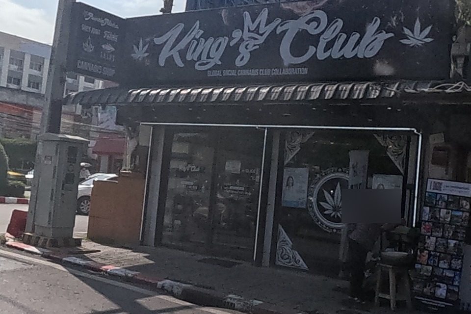A cannabis club called King's Club occupies a dark shopfront under a black sign, next to a small key-cutting and lock-repair stall.