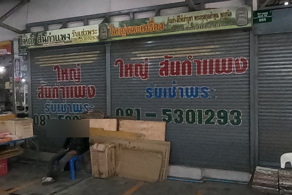 The shutters of ใหญ่ สันกำแพง with its name and phone painted large; open casing counters beside it.
