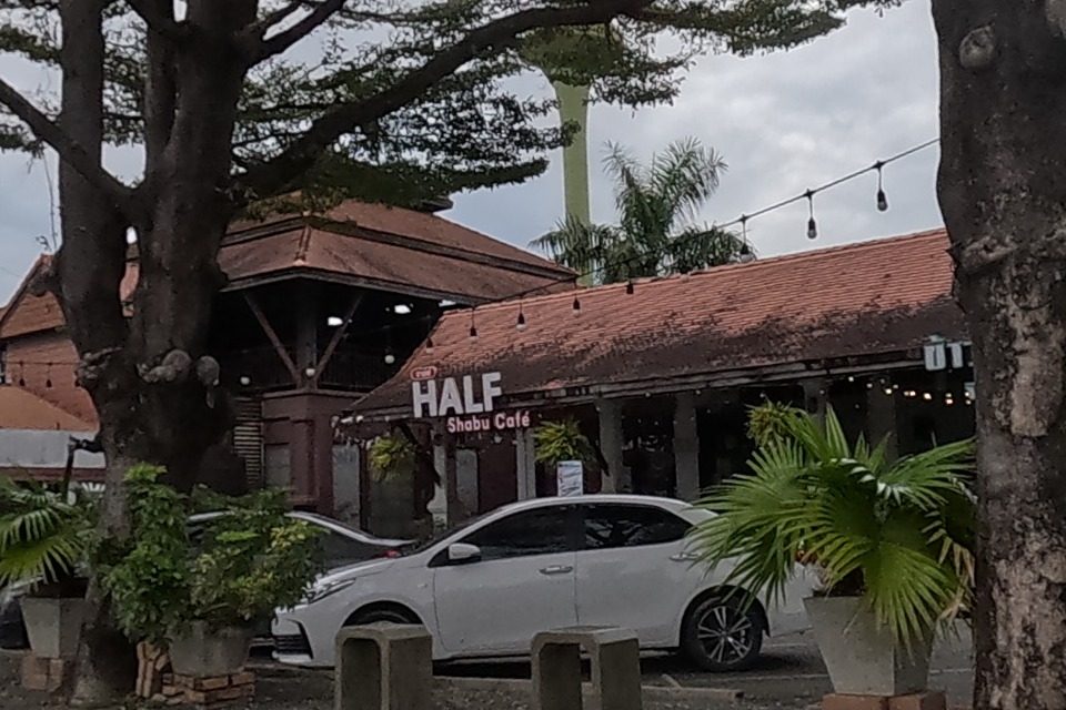 The Jing Jai Village market row of shops under old tiled roofs, with a shabu cafe, a candied-sweets stall, and a farmers-market event banner.