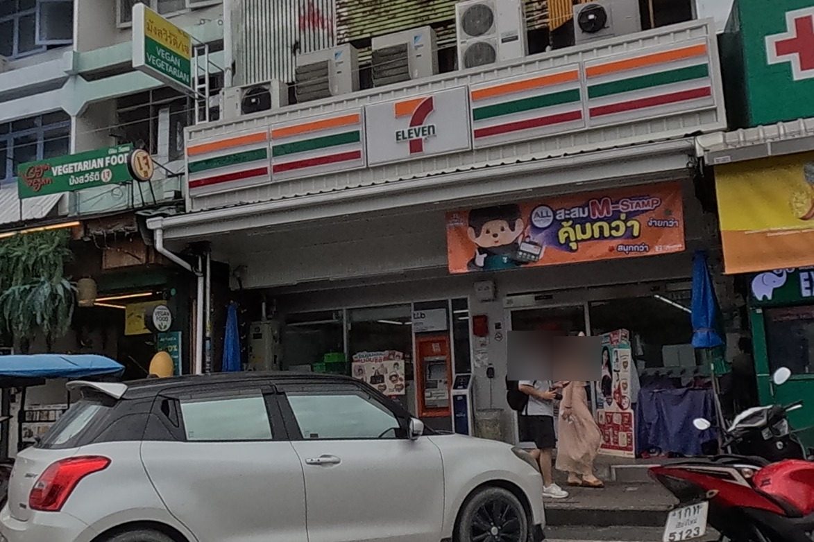 A 7-Eleven convenience store next to a pharmacy with a currency-exchange and ATM booth.