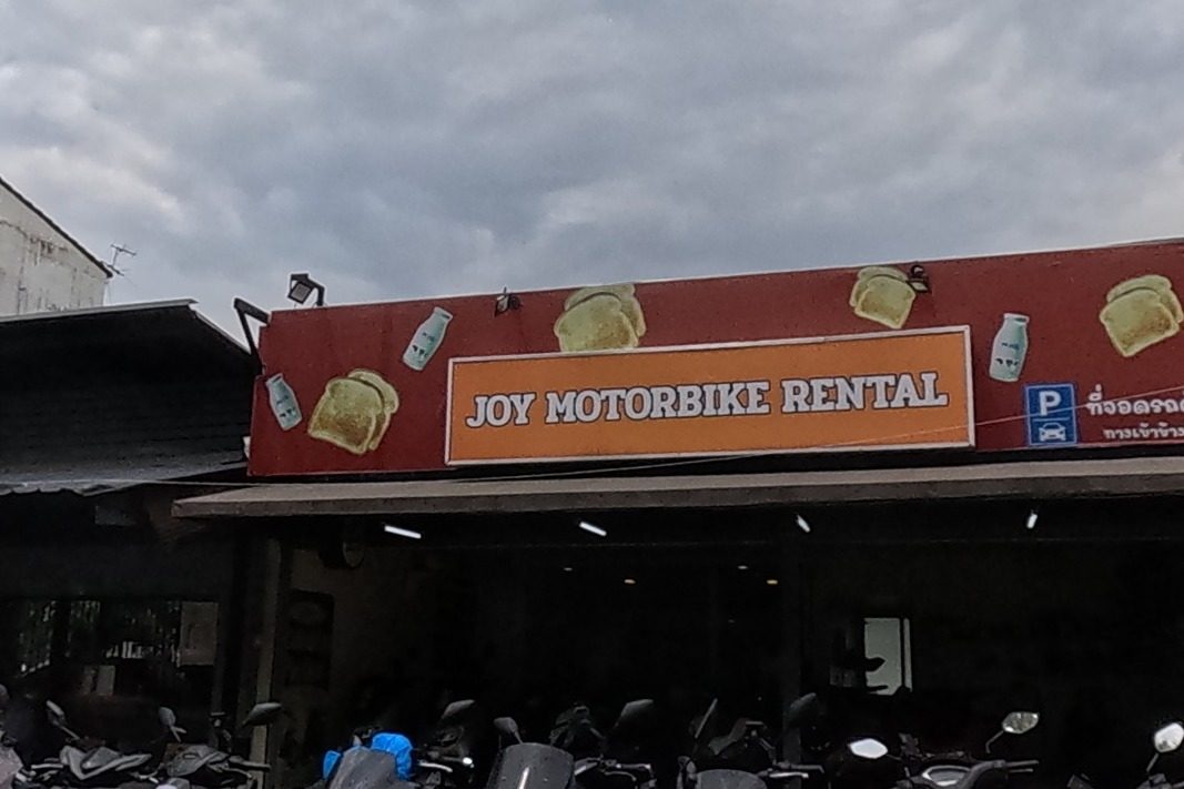 A motorbike rental shop next to a restaurant branded with a Coca-Cola sign.