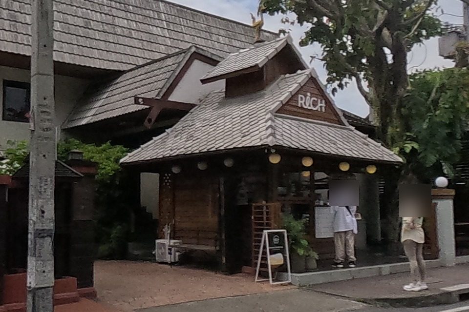 A teak Lanna-style restaurant with a carved gable and a tiled roof, at the mouth of a side lane.