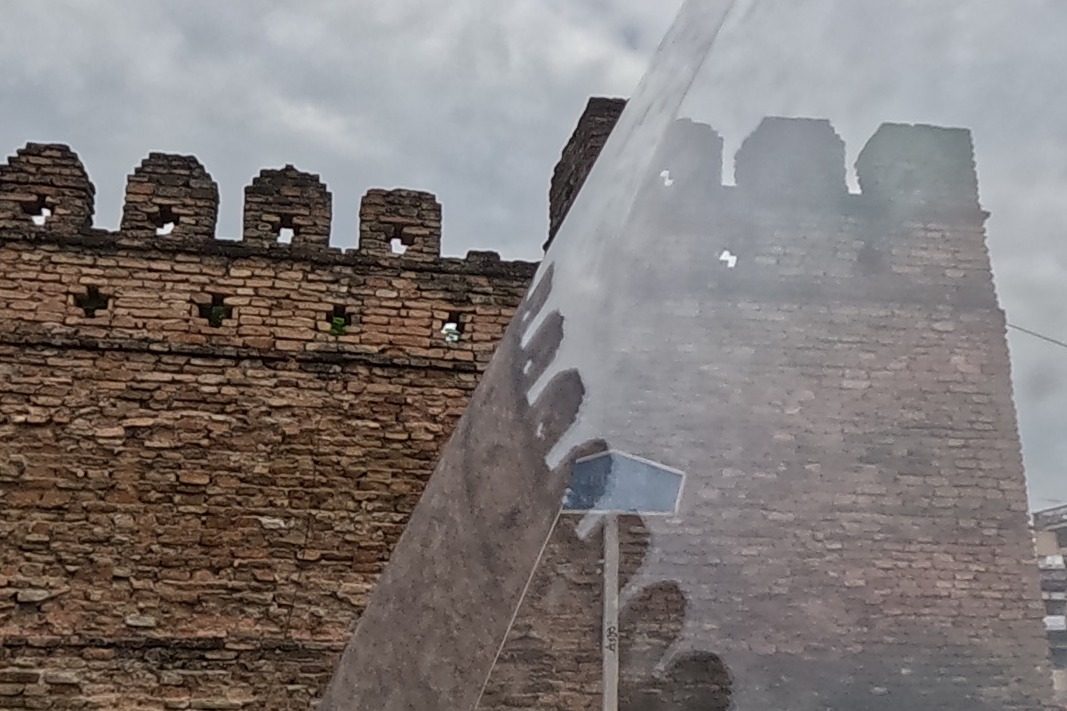 The crenellated corner bastion of the old city wall, brick battlements against the sky.
