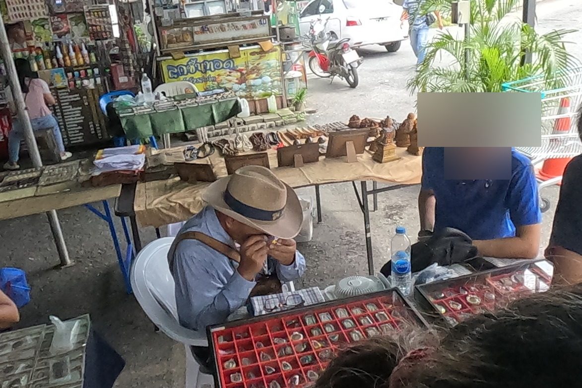 A dealer checks an amulet with a loupe