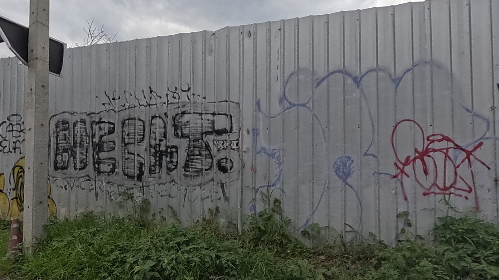 Bold black tag with red and blue scribble tags on a metal fence