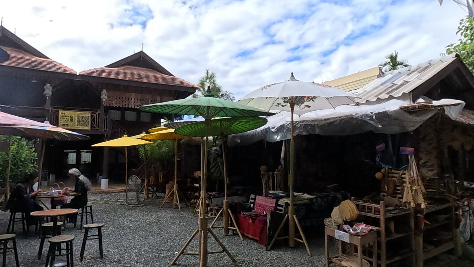Paper umbrellas before a teak house — Chamcha Market, San Kamphaeng