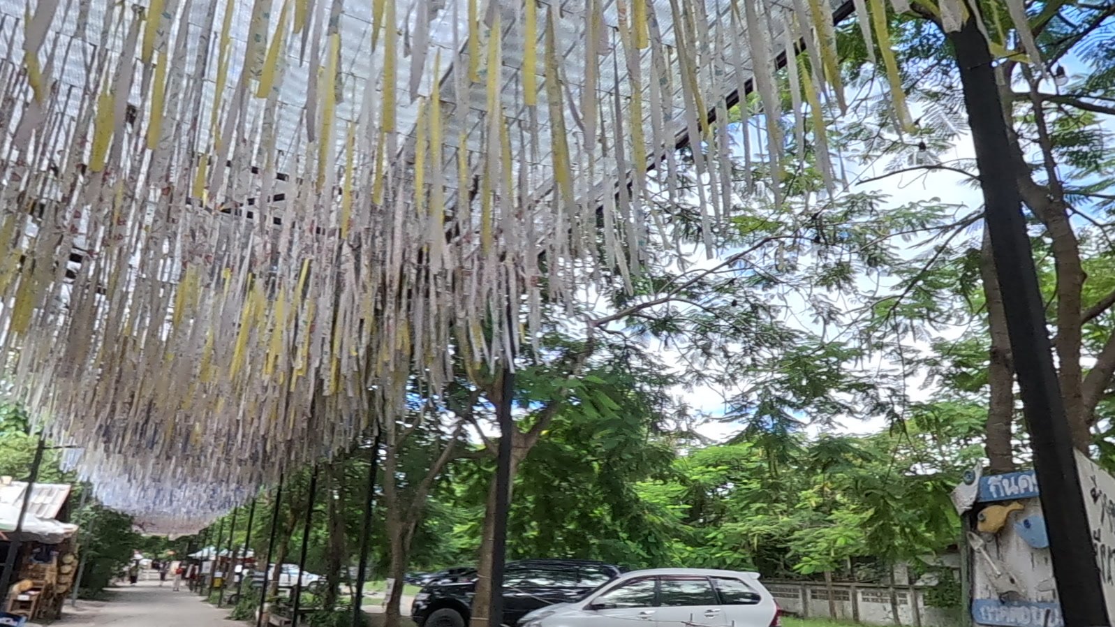 A ceiling of paper streamers over the lane — Chamcha Market, San Kamphaeng