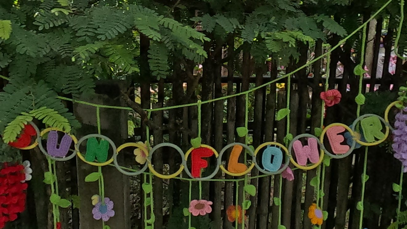 Crocheted SUNFLOWER garland on a bamboo fence — Chamcha Market, San Kamphaeng