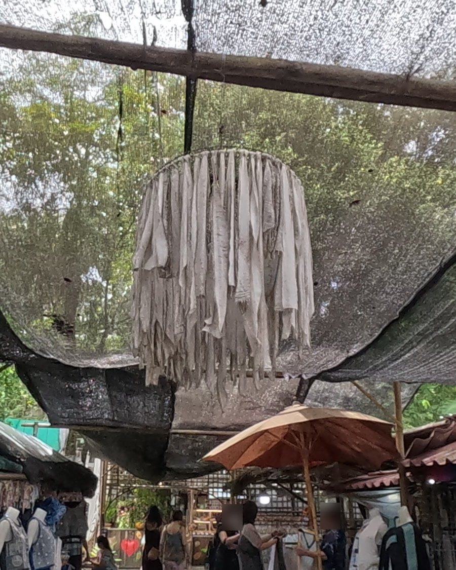 A lantern of pale cloth strips over the lane — Chamcha Market, San Kamphaeng