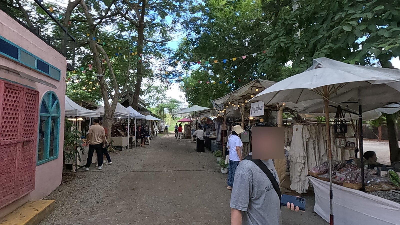 A row of white stalls under the trees — Chamcha Market, San Kamphaeng
