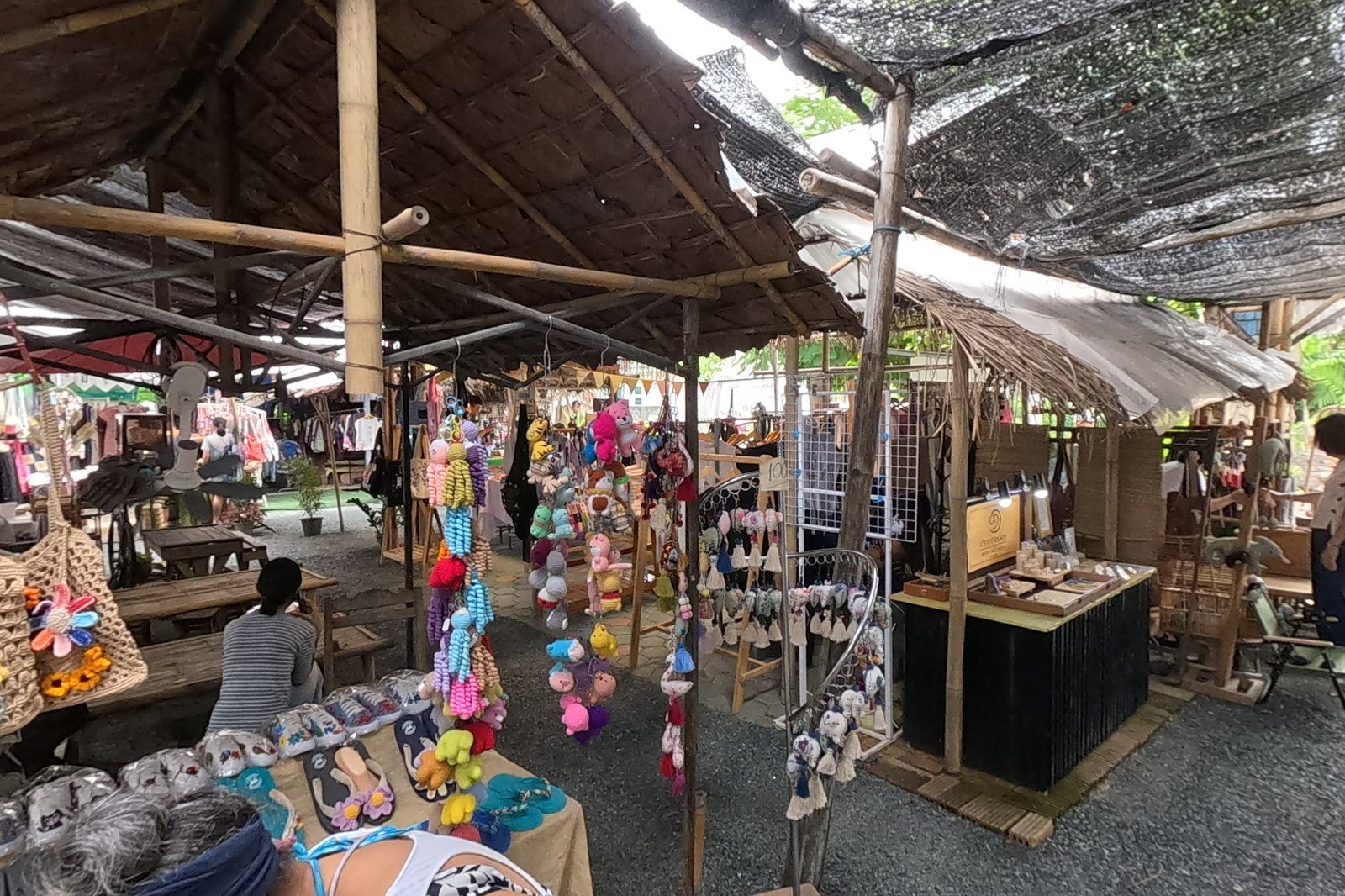 Crochet dolls hanging under a thatched stall — Chamcha Market, San Kamphaeng