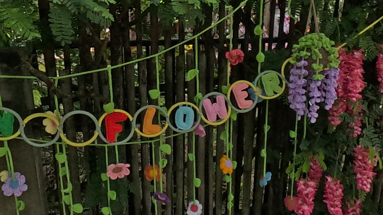 A crocheted flower garland on a black fence — Chamcha Market, San Kamphaeng