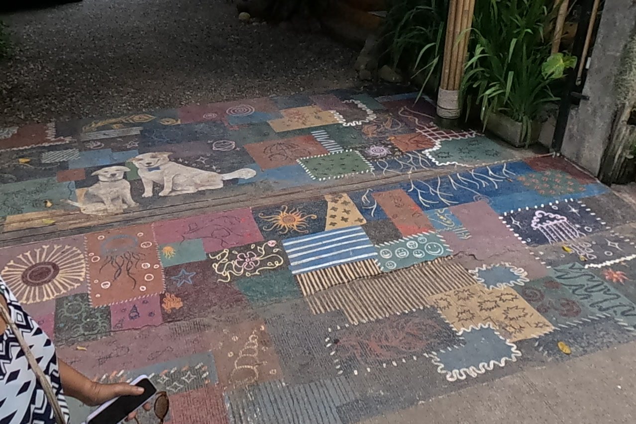 A patchwork mural painted on the ground — Chamcha Market, San Kamphaeng