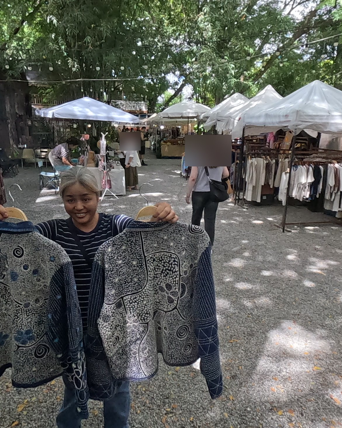 The shopkeeper shows her indigo jackets — Chamcha Market, San Kamphaeng