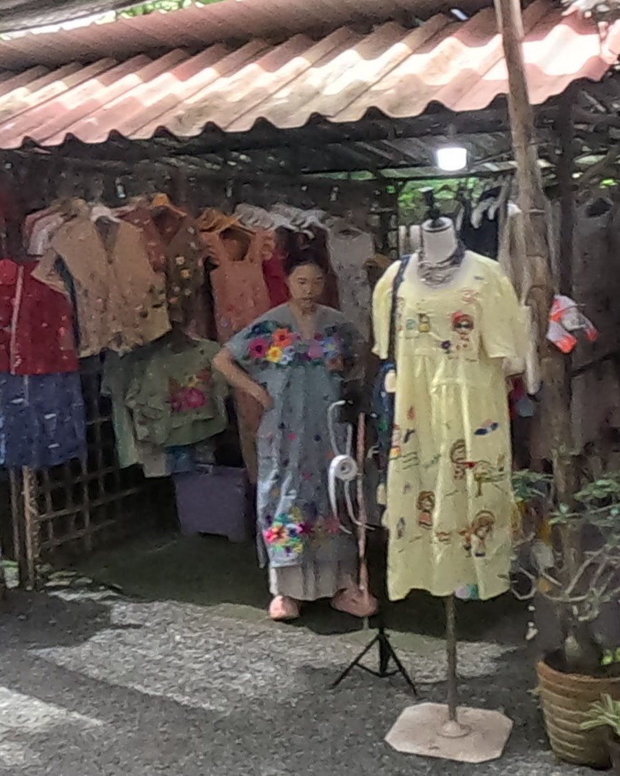 In the doorway of the embroidered-clothing shop — Chamcha Market, San Kamphaeng