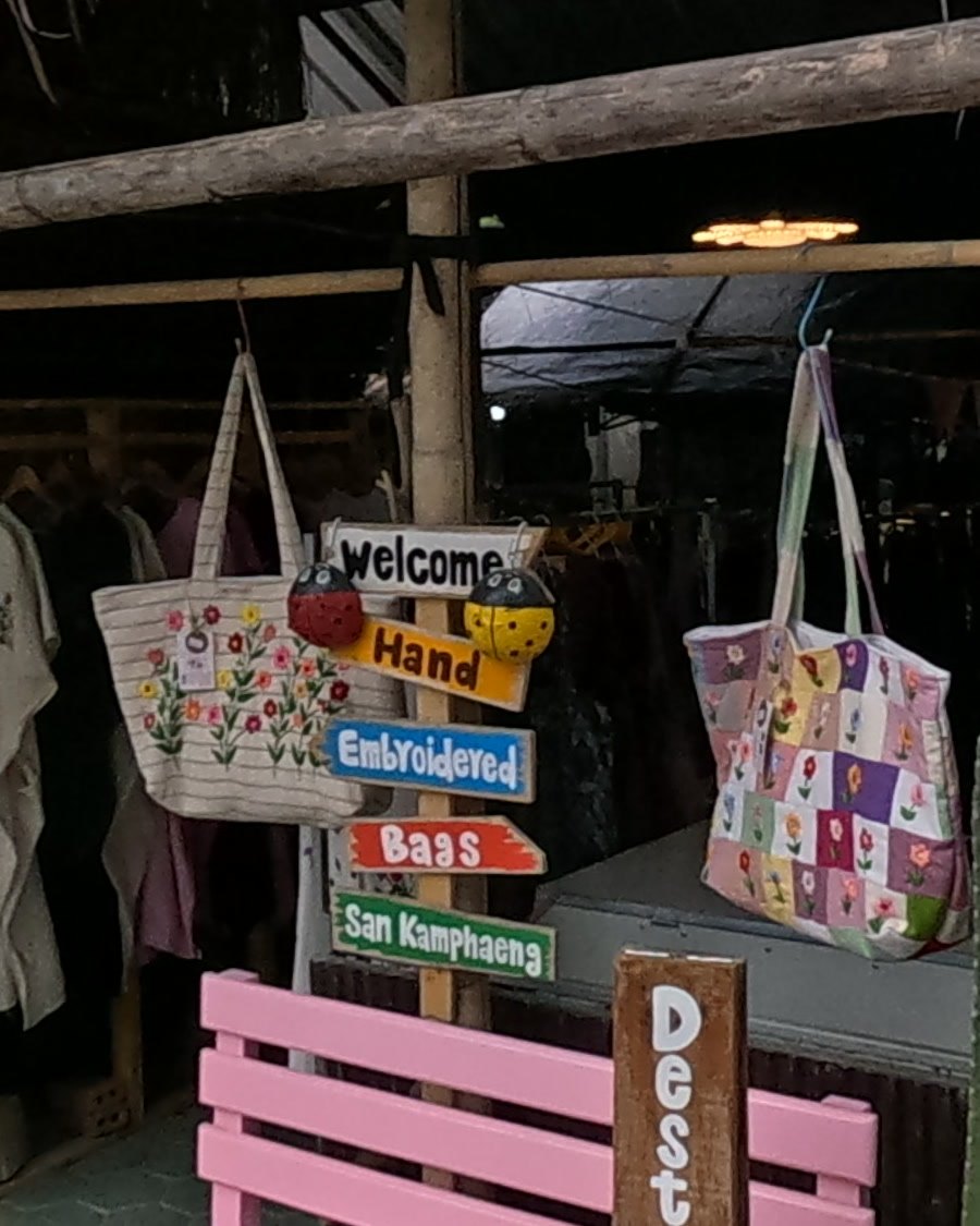 Welcome signpost at an embroidered-bag stall — Chamcha Market, San Kamphaeng