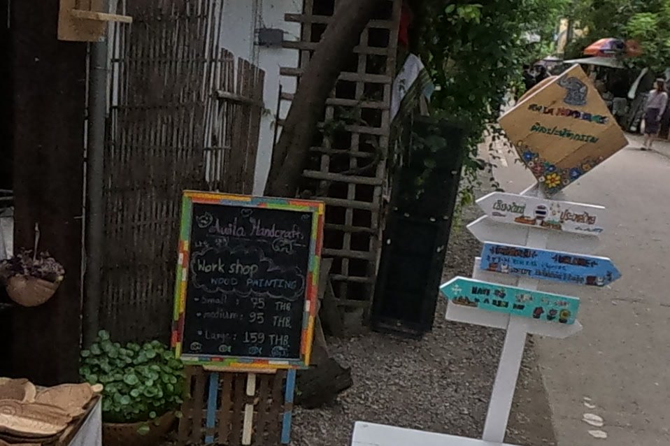 Awila's wood-painting workshop board and signpost — Chamcha Market, San Kamphaeng