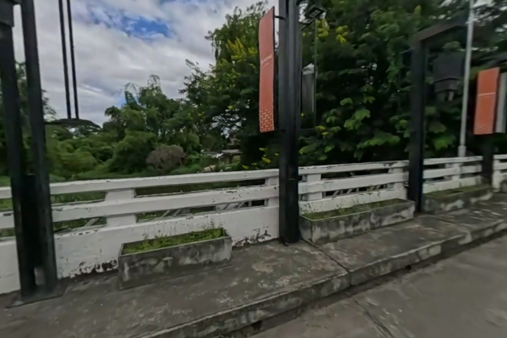 The bridge over the river: white balustrade, black lamp posts, orange pennants — San Kamphaeng
