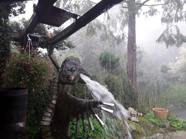 A home-made gargoyle on a rain gutter in Germany, in a downpour.