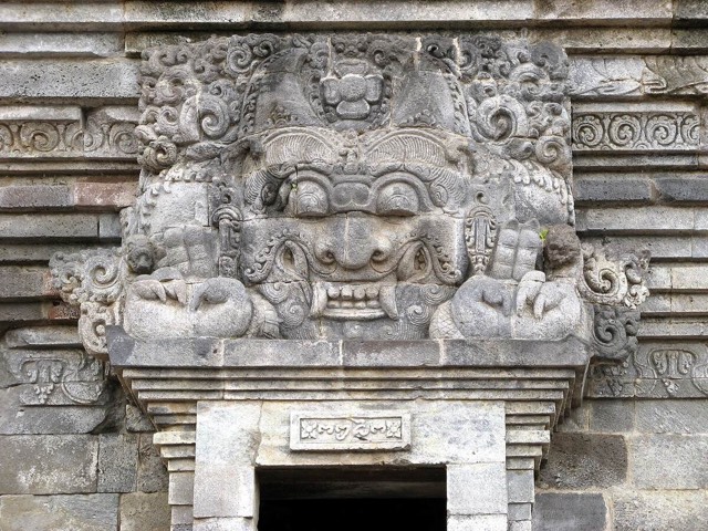 A horned, fanged kala face crowning a temple doorway at Candi Panataran in East Java, dated by its inscription to 1369 AD.