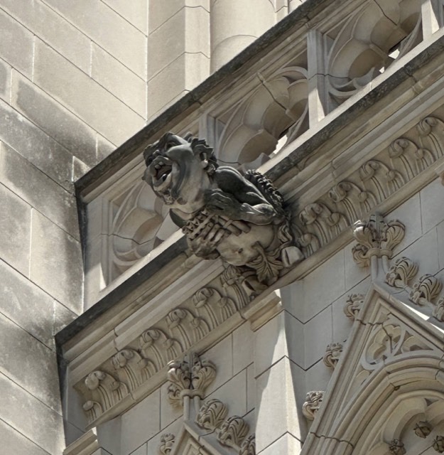 A grinning grotesque holding panpipes, projecting from a parapet of Washington National Cathedral in Washington, D.C.