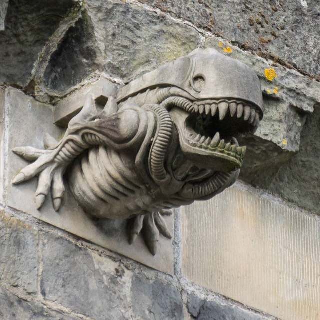 A gargoyle carved in the 1990s with a snarling Alien-like head, jutting from the stone wall of Paisley Abbey in Renfrewshire, Scotland.