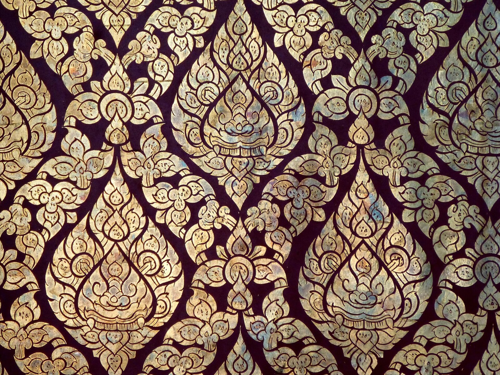 Gilt-on-lacquer (lai rot nam) door panel at Wat Kasattrathirat, Ayutthaya: kranok flames packed into a repeating all-over pattern.