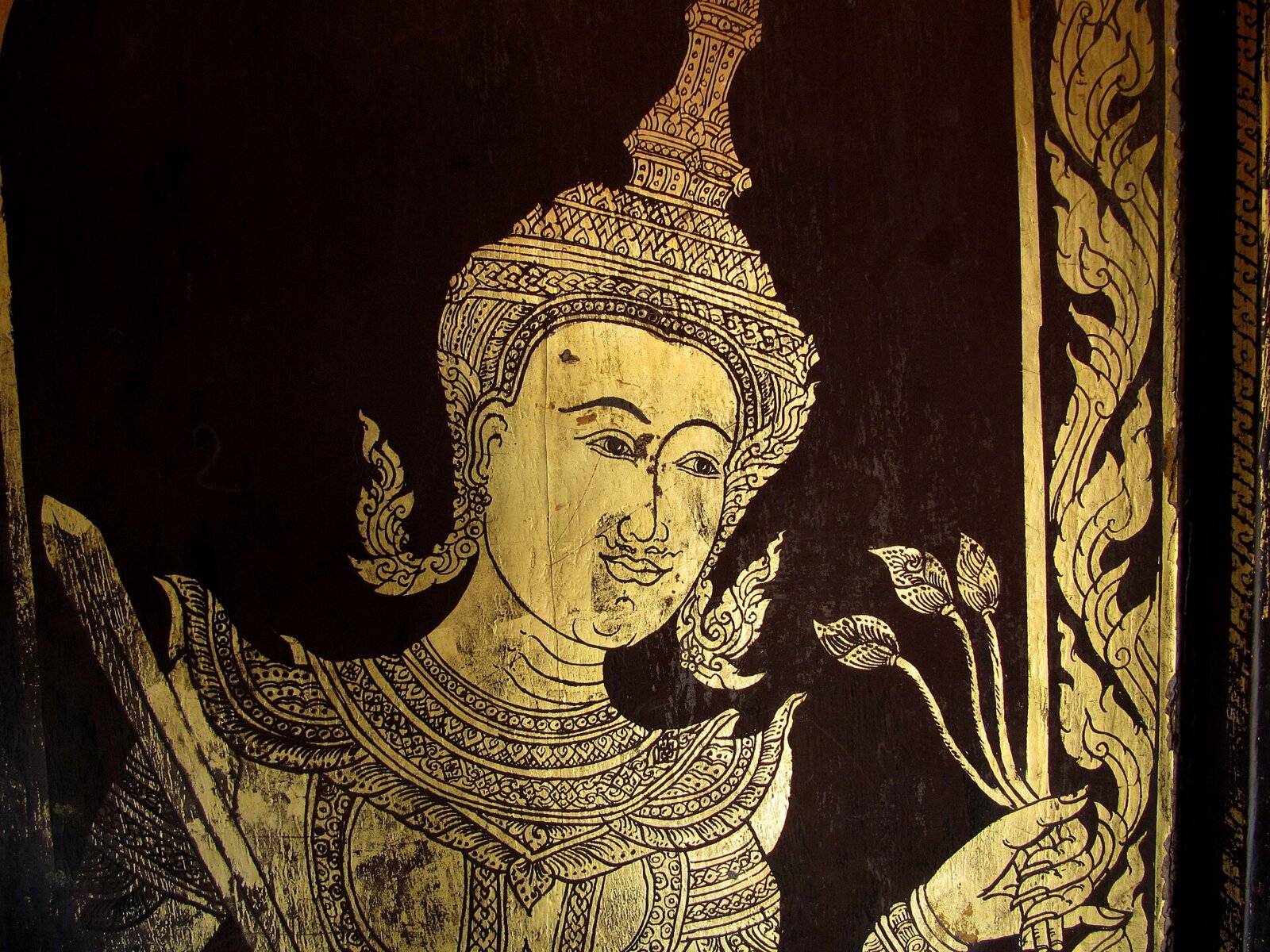 Lai rot nam door panel at Wat Phra That Doi Suthep, Chiang Mai: a gilt deity framed by a kranok border.