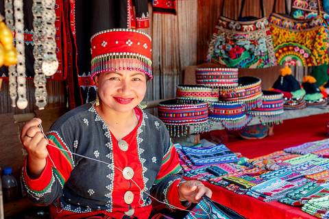 Karen tribal woman in traditional clothes sitting and sewing, ethnic village, Pattaya, Thailand.