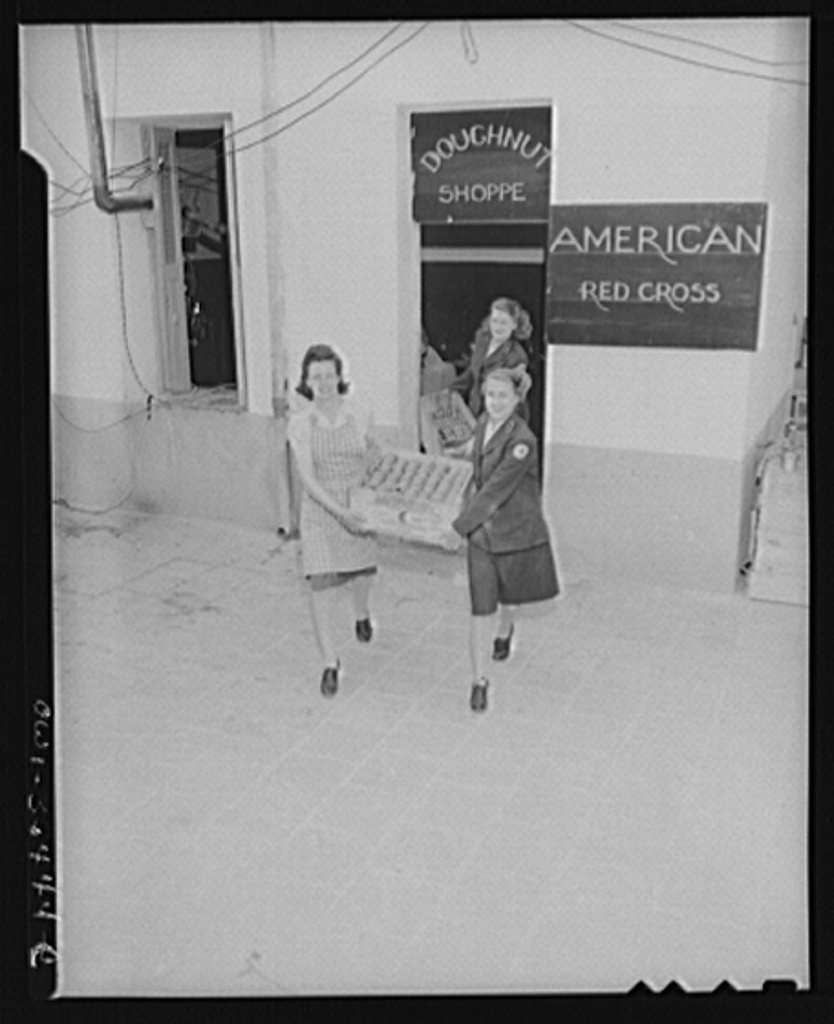 Constantine (vicinity), Algeria. A Red Cross girls carrying fresh doughnuts from an improvised kitchen to waiting clubmobile units which will carry doughnuts and coffee out to for bombers' crews who h